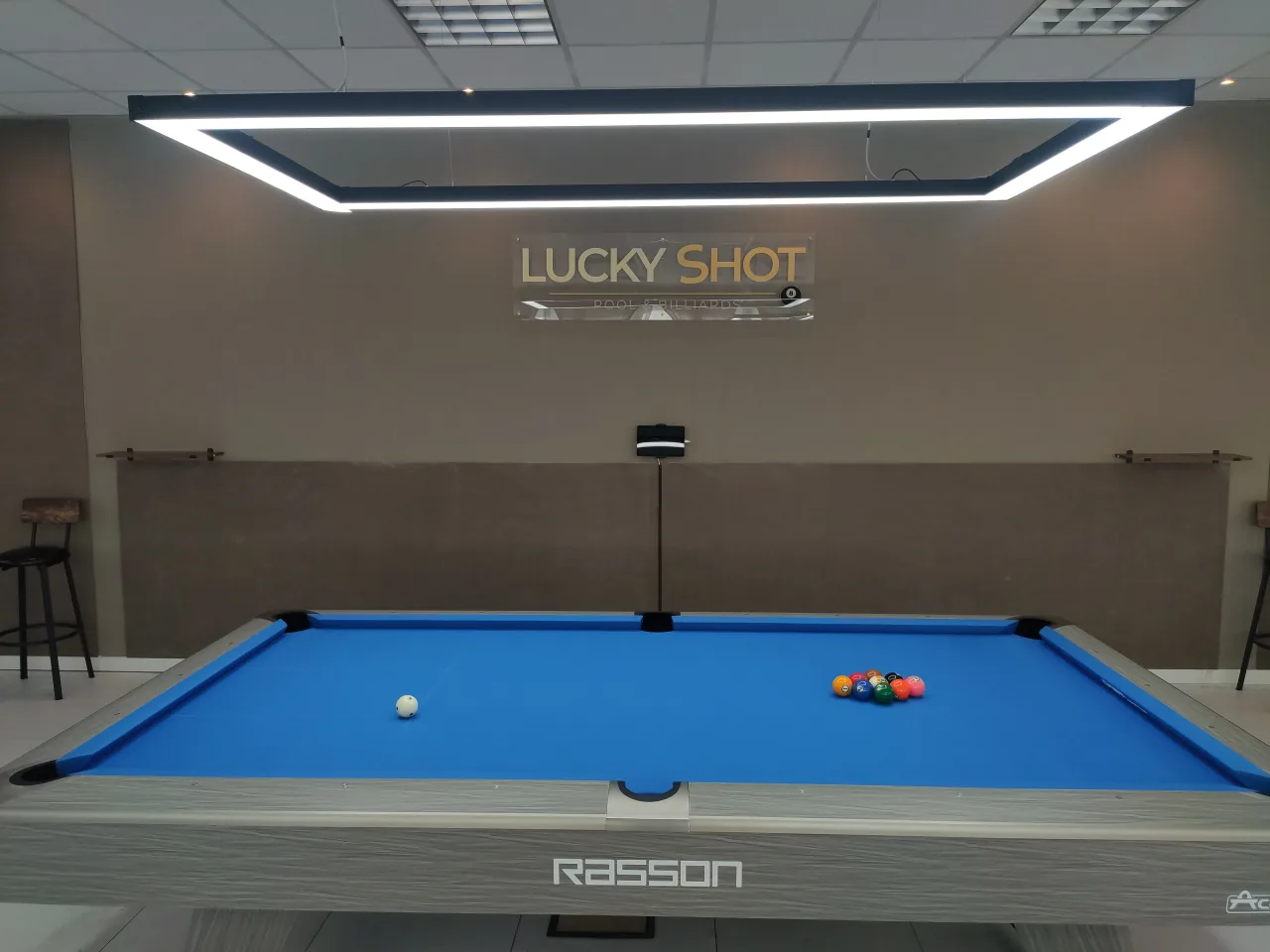 Tavolo Rasson Acurra con logo Lucky Shot sulla parete